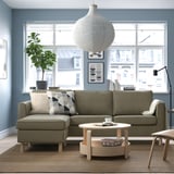 Modern living room: green PÄRUP sofa, large window, white lamp, plant, coffee table, rug.