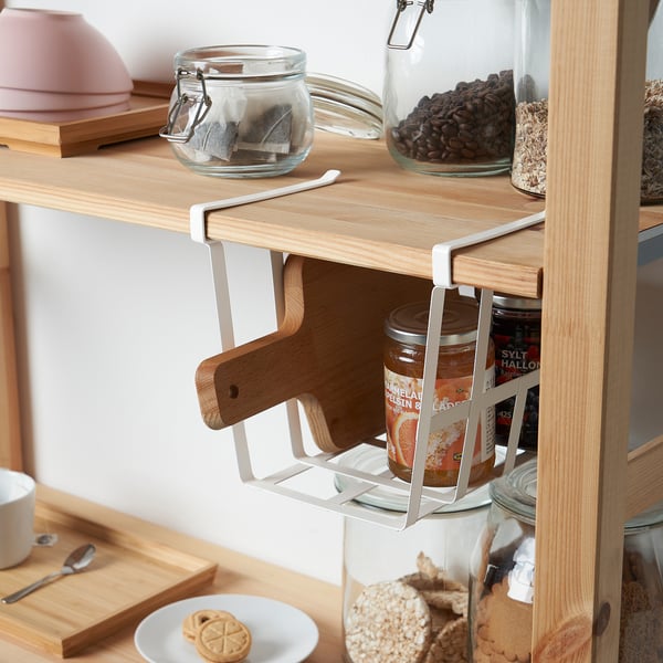 Shelf organizer clips on basket for space optimization, holding jars and wooden utensils beneath shelf.