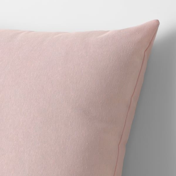 A close-up of a pink cushion against a white wall, showcasing its soft, recycled fabric texture.