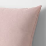 A close-up of a pink cushion against a white wall, showcasing its soft, recycled fabric texture.