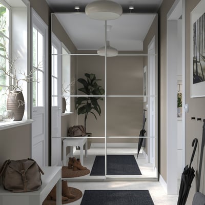 A modern, minimalist entryway with gray and white decor. Include a glass-front storage unit, a large indoor plant, and stylish accessories.