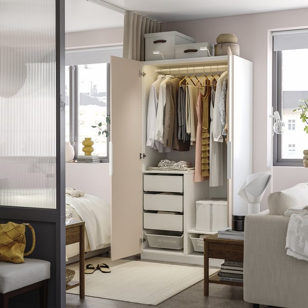 Open wardrobe displaying clothes hangers, storage boxes, and drawers. Integrated lighting highlights garments and accessories within.