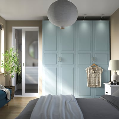 PAX wardrobe, tall blue, wood texture, door handles, hangs shirt, near bed, beside lamp.