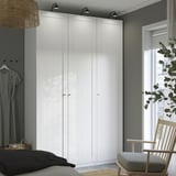 Bright room with large white PAX wardrobe. Bed, chair, and window with plant nearby.