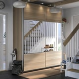 Modern entryway with wooden PAX storage. Stairs, skates, bags, and a clock. Clean, organized look.