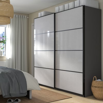 Modern bedroom with large black & grey PAX wardrobe, sliding doors, emphasizing size and functionality.