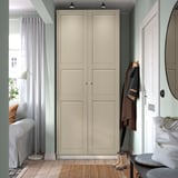Modern gray PAX wardrobe with two doors, minimalist design, near white door, mirror, and chair.
