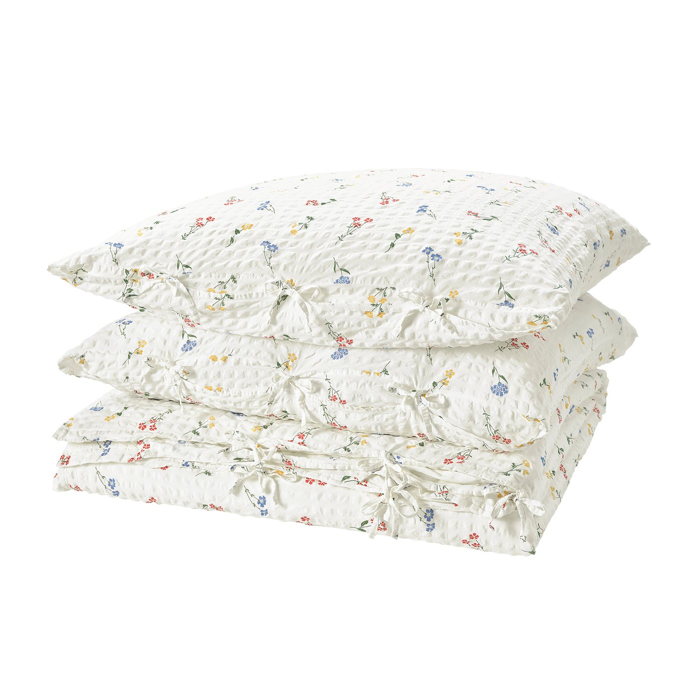 A stack of white, seersucker duvet covers with colorful floral prints, neatly folded and stacked.