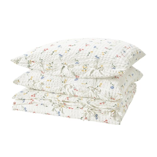 A stack of white, seersucker duvet covers with colourful floral prints, neatly folded and stacked.