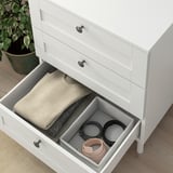 A white PLATSA chest with folded clothes and accessories, showing drawer organization.