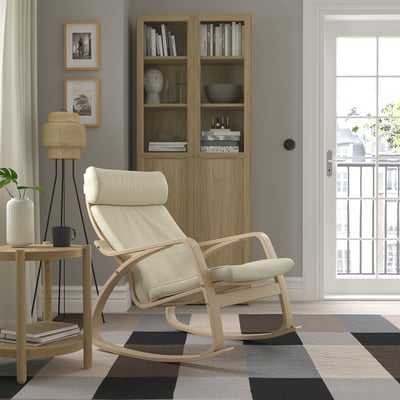 Modern living room with rocking chair, cabinet, rug. Chair has headrest & cushions. Balcony doors & decor visible.