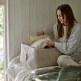 Woman organizing clothes into beige PURRPINGLA storage case.