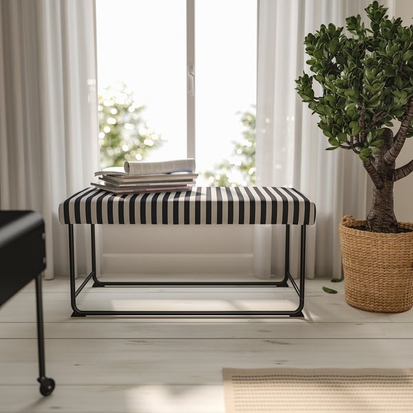 Modern living room with RÄVSAL bench. Black & white striped seat, metal legs, large, near potted plant.