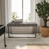 Modern living room with RÄVSAL bench. Black & white striped seat, metal legs, large, near potted plant.