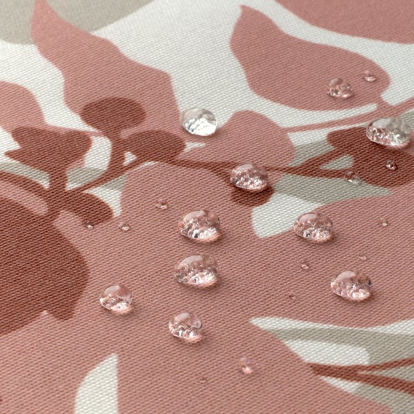 Droplets on patterned pink tablecloth, showcasing water-resistant coating.