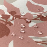 Droplets on patterned pink tablecloth, showcasing water-resistant coating.
