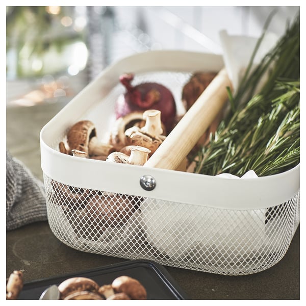 White RISATORP storage bin with mesh design, containing mushrooms, onion, and herbs, has a handle for easy transport.