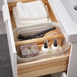 Organized bathroom drawer with RISATORP divider: towels, hairbrushes, bottles, and accessories neatly stored.