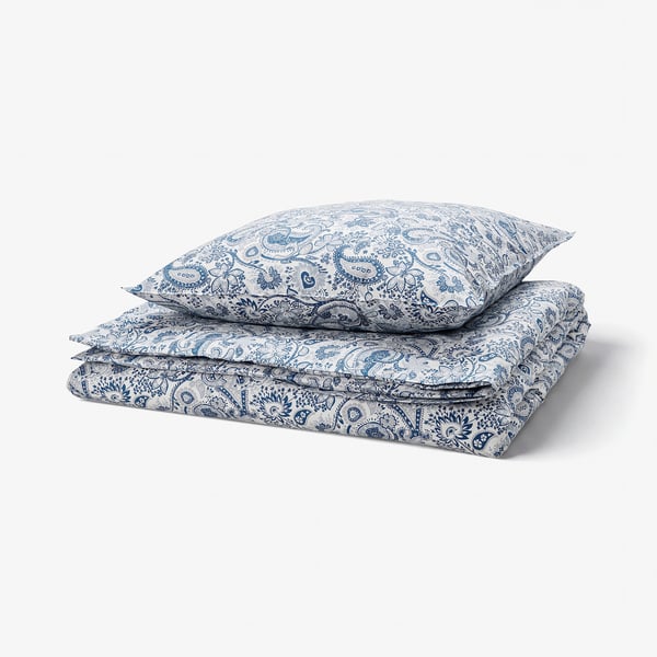 Folded blue paisley-patterned bed linens with decorative buttons, light and opaque, made of 80% cotton and 20% viscose.