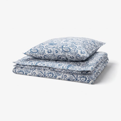 Folded blue paisley-patterned bed linens with decorative buttons, light and opaque, made of 80% cotton and 20% viscose.