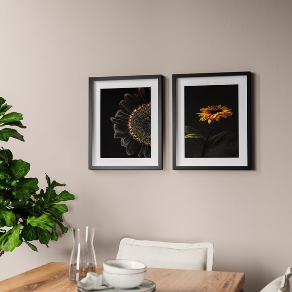 Two sunflower photos above table with teacup, napkin, and vase.