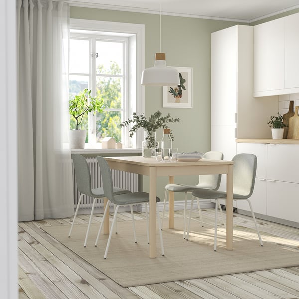Modern dining area with extendable table, 4 light gray chairs, pendant light, floral print, and large window.