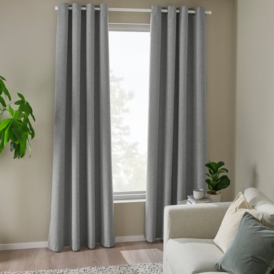 Modern living room with grey curtains, blocking light. Light sofa, green plants. Curtains larger than window.