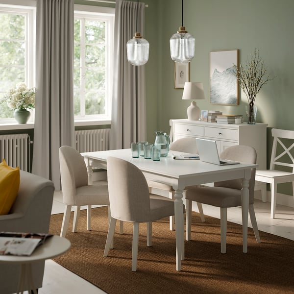 Modern living room with ROSENTORP table, beige chairs, and natural decor.