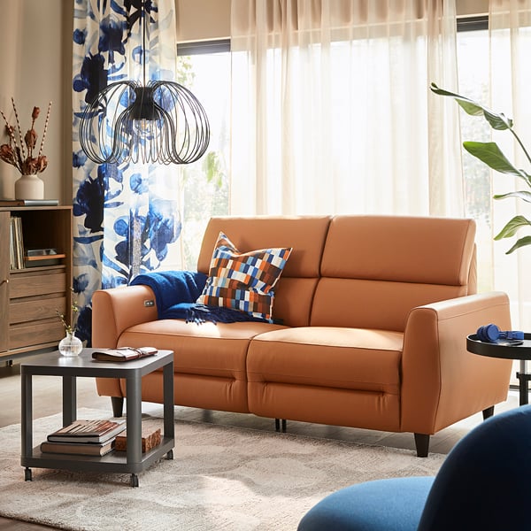 Living room: orange recliner, blue throw, floral curtain, coffee table, plant.