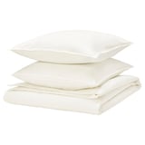 Stack of white bed linens: one folded duvet & two pillows, simple, crisp.