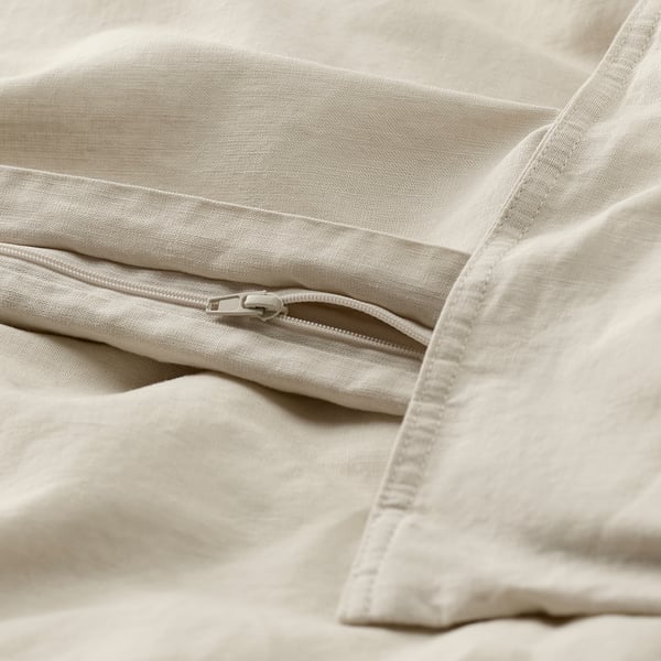 Close-up of a beige duvet cover with a zipper, showcasing its textured linen-cotton blend and functional closure.