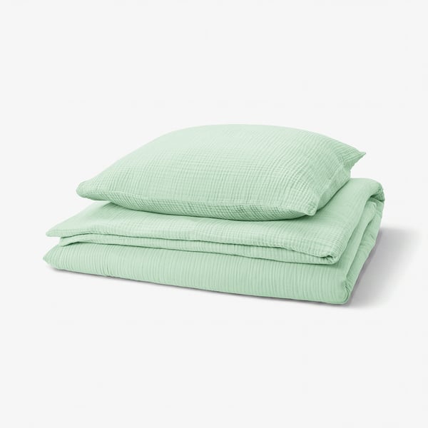 A green SCHERSMIN bedding set featuring a duvet cover and pillowcases made from 100% organic cotton with a wavy muslin texture.