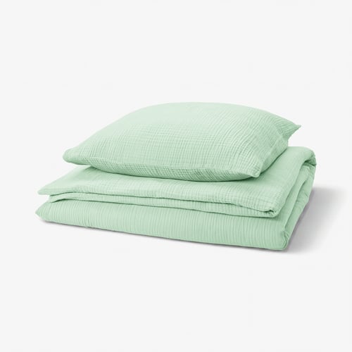 A green SCHERSMIN bedding set featuring a duvet cover and pillowcases made from 100% organic cotton with a wavy muslin texture.