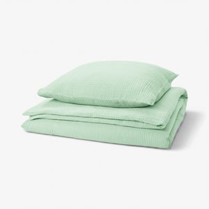 A green SCHERSMIN bedding set featuring a duvet cover and pillowcases made from 100% organic cotton with a wavy muslin texture.