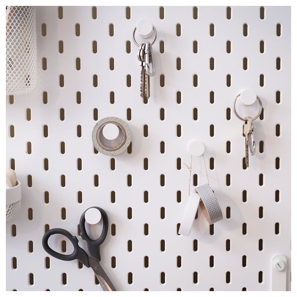 SKÅDIS white pegboard with black hooks holds keys, scissors, and tape. Organized and modern wall storage.