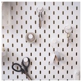 SKÅDIS white pegboard with black hooks holds keys, scissors, and tape. Organized and modern wall storage.