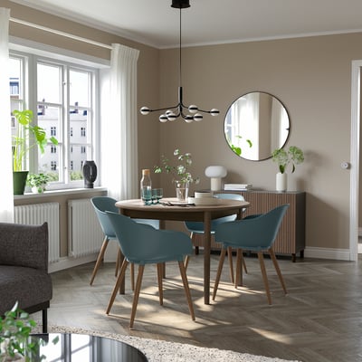 SKANSNÄS 4-seat dining set with extendable table, grey-blue chairs, plates, glasses, vase, mirror, and decor.
