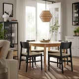 Modern dining area with SKANSNÄS light wood table surrounding by black chairs, unique pendant light, large window.