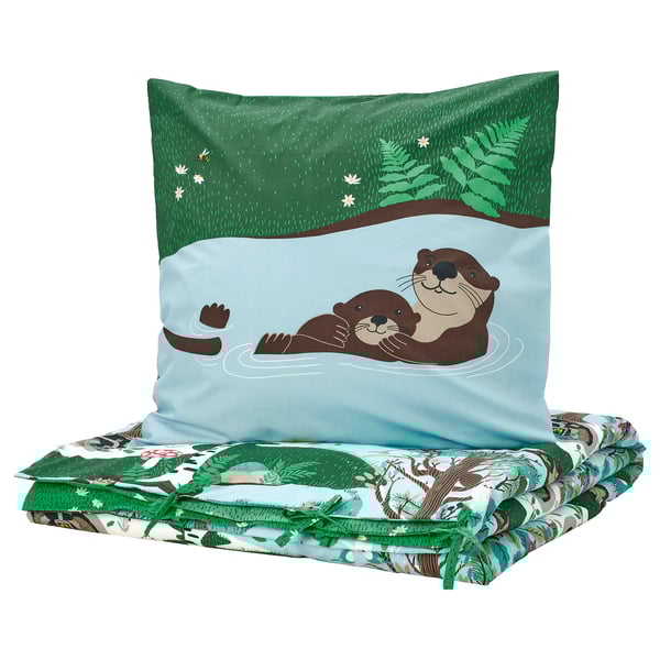 Colorful forest-themed kids bedding set: blue pillow with playful otter print, matching green-patterned blanket. Made from soft cotton and viscose.