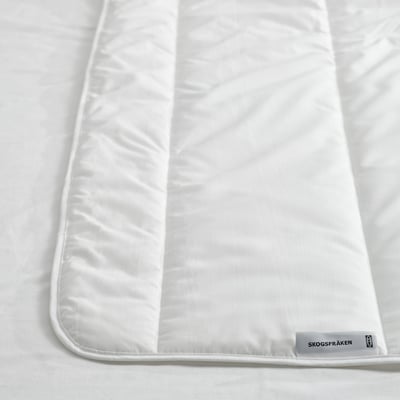 White duvet on a bed, made from breathable recycled polyester and lyocell fabric, offering a soft and comfortable sleeping experience.
