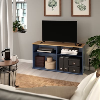 Modern living room with blue SKRUVBY tv stand, flat-screen tv, books, coffee, and plants.