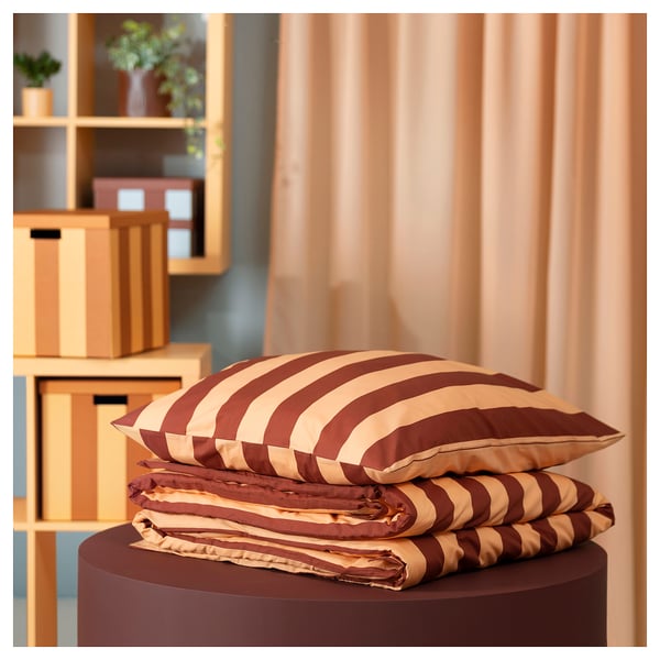 SLÅNHÖSTMAL striped bedding on stand, with curtains and storage in background.