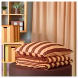 SLÅNHÖSTMAL striped bedding on stand, with curtains and storage in background.