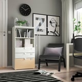 A modern home office with a white SMÅSTAD bookshelf, featuring a black office chair, a black clock, and framed artwork on the wall.