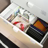 Open storage drawers with white handles, filled with gaming items like controls and games.