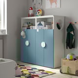 Kids room with SMÅSTAD white & blue wardrobe, shelves, toys, books. Soft-close hinges, by window, stable.