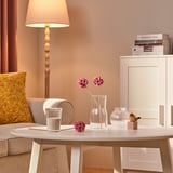 A cozy living room with beige walls, a flower vase on a table, and a lampshade.