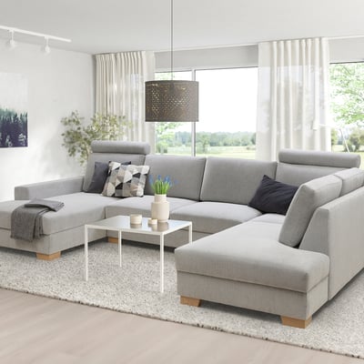 Grey SÖRVALLEN sectional sofa in living room, with cushions, blanket, coffee table, and large windows.