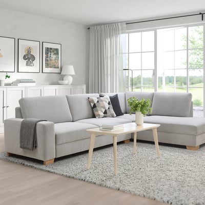 Modern minimalist living room with large l-shaped gray sofa, side table, neutral decor.