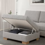 Modern grey sofa with lifting storage compartment, revealing folded blankets inside.